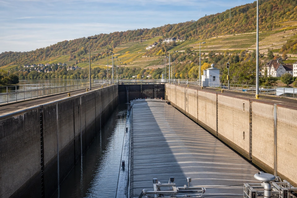 Langes Schleusenbecken mit hohen Betonwänden, darin ein beladenes Binnenschiff vor geschlossenem Tor (mit AI erstelltes Bild)