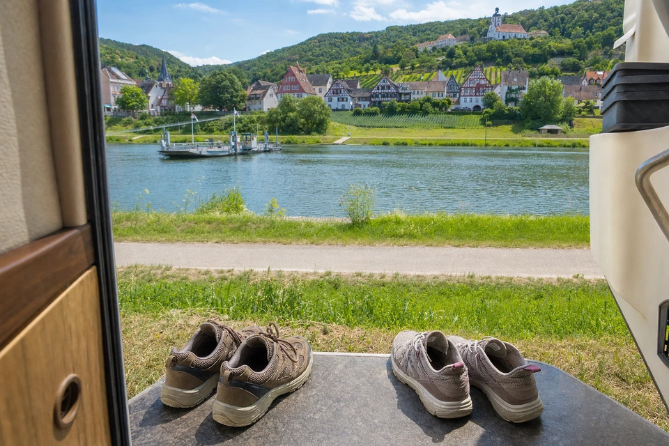 Zwei Paar leichte Wanderschuhe trocknen auf der warmen Steinstufe eines Wohnmobils (mit AI erstelltes Bild)